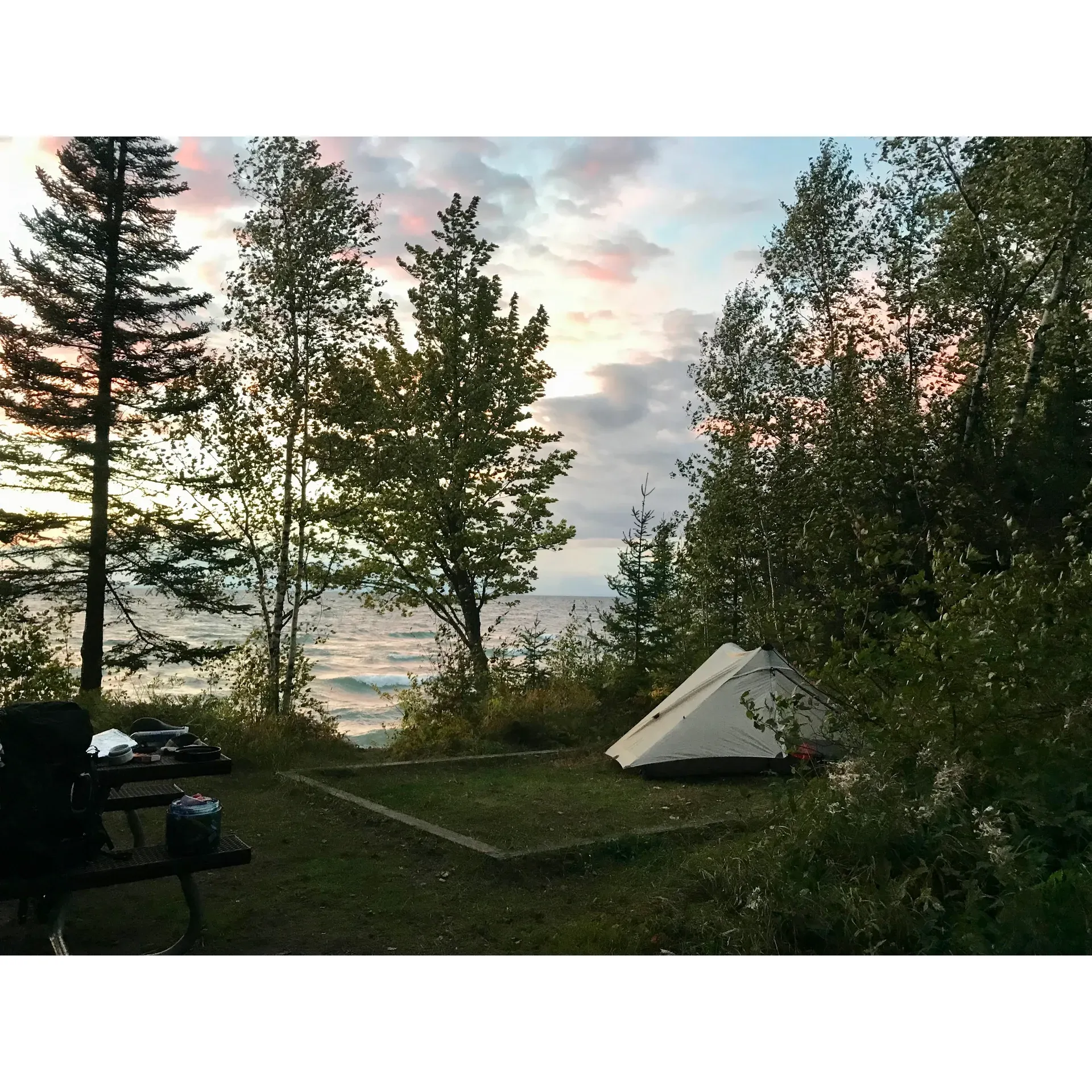 Overlooking the pristine waters of Lake Superior, Lakeshore Trail Campsite emerges as an idyllic retreat for the outdoor enthusiast. This secluded backpack campsite is a mere 30 feet from the magnificent shorelines of Lake Superior, offering an immersive experience for nature lovers.

Guests can revel in the simplicity and quietude of the wilderness with facilities that blend conveniently into the setting. The campsite is well-equipped with a sturdy picnic table perfect for enjoying a meal amidst the great outdoors, while the fire pit provides a cozy gathering space to share stories and roast marshmallows under the starlit sky.

For your comfort and convenience, the site includes a dedicated tent pad to assure a level foundation for your home away from home. A pit toilet is available, ensuring basic amenities are on hand without compromising the natural aesthetic of the surroundings. Additionally, the provision of a bear box for safe food storage demonstrates a thoughtful consideration for both camper safety and wildlife preservation.

Sea kayakers often grace the nearby beach during the day and evening, adding a sense of community and camaraderie to the serene setting. This boutique campsite experience is recognized as a treasured spot, inviting visitors to a private beachfront that rewards those who have made the journey from Meyers Beach with tranquility and unspoiled views.

Though rates and extensive details of the campground may not be immediately accessible via the app, the allure of Lakeshore Trail Campsite lies in its unparalleled location, essential amenities, and the serene joy of lakeside camping. It's a place where memories are made, and the beauty of nature speaks for itself. Description by ChatGPT.