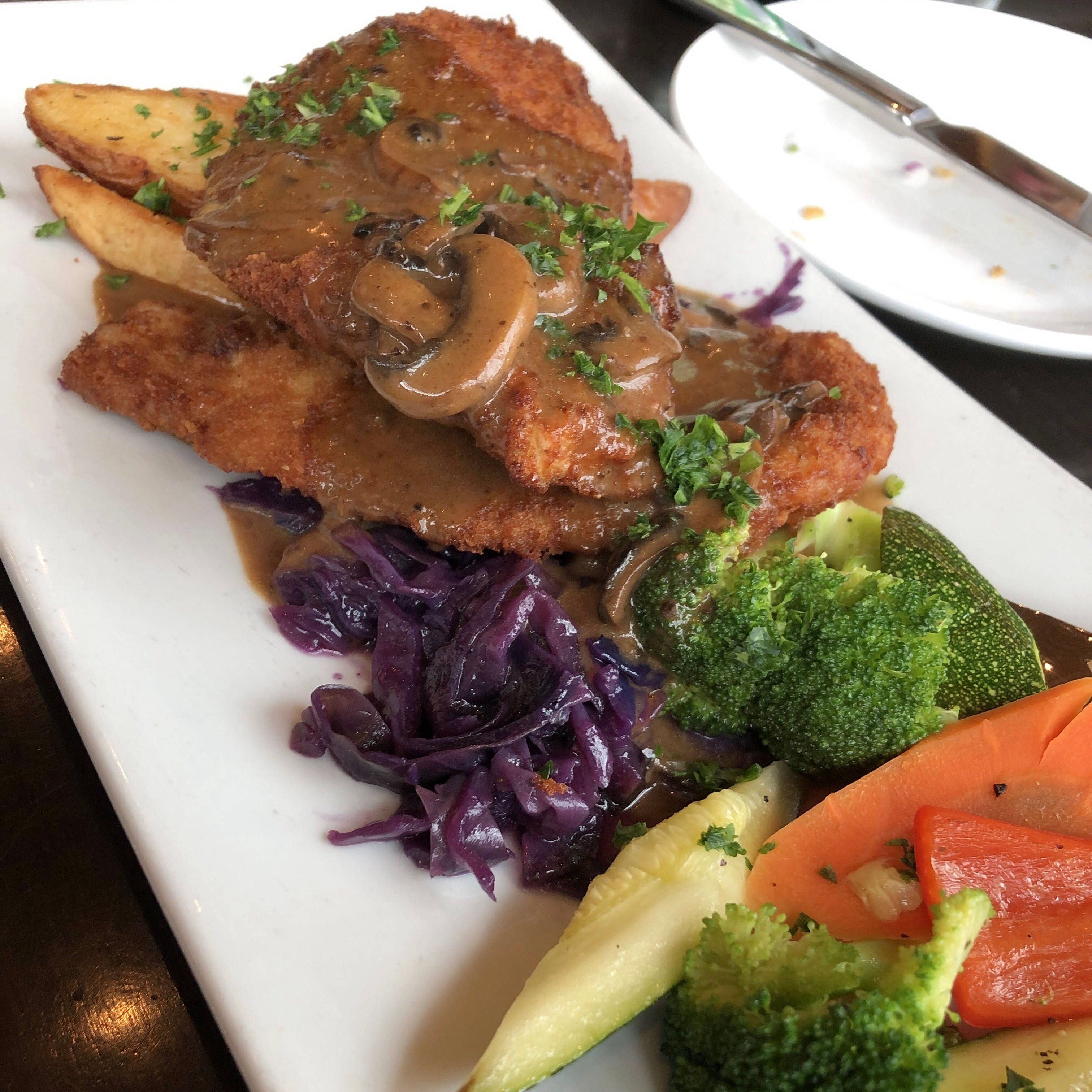breaded pork cutlets in a creamy mushroom demi glace served with braised cabbage and roasted potatoes