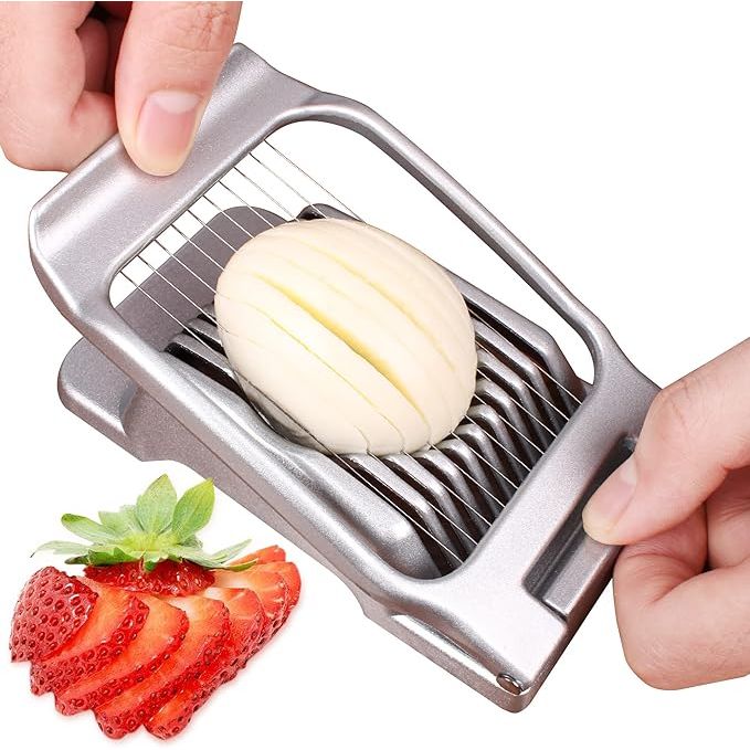 A kitchen essential, the egg slicer is a versatile tool designed for effortlessly slicing hard-boiled eggs with precision. Crafted from heavy-duty aluminium and equipped with sharp stainless steel wires, this durable gadget can slice through various foods like strawberries, mushrooms, and soft fruits.