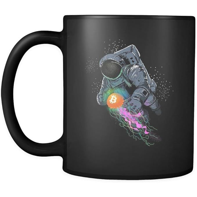 The Bitcoin BTC Crypto Space - Crypto Blockchain 11oz Funny Black Coffee Mug features a unique design of an astronaut holding a jelly cryptocurrency, making it a fun and eye-catching gift for friends who are interested in the world of cryptocurrencies.