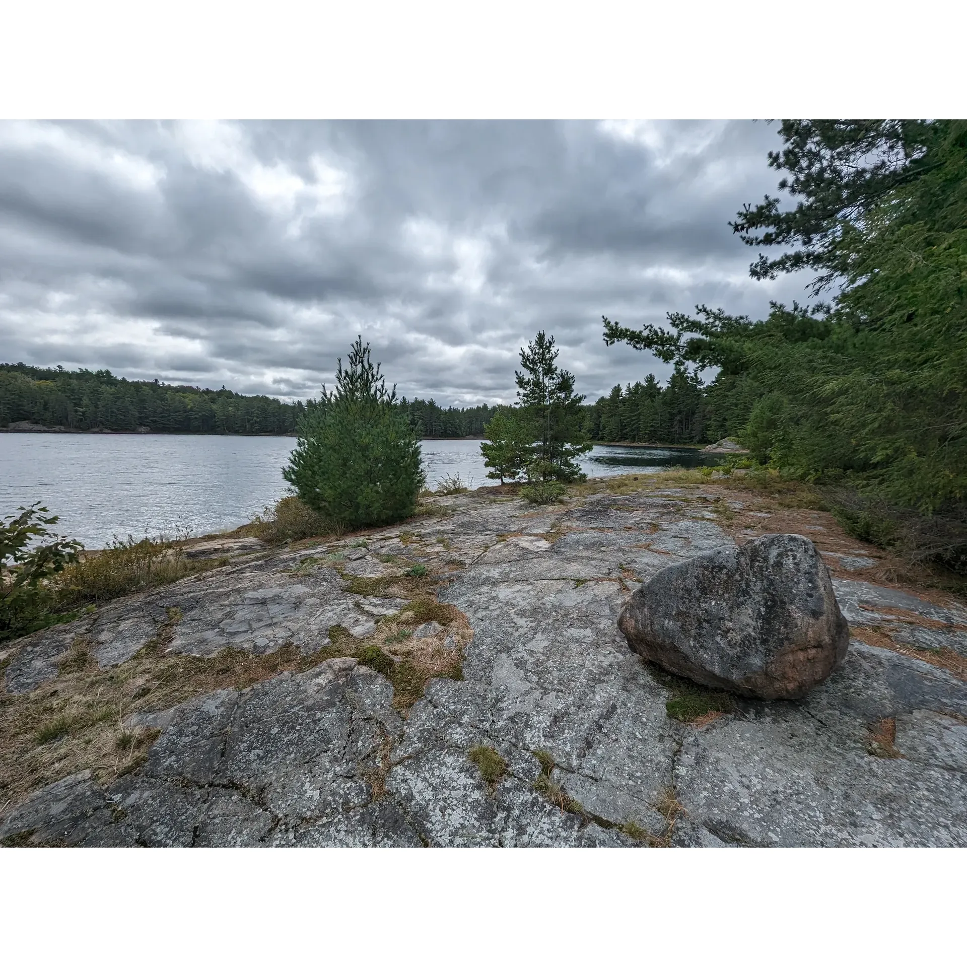 Backcountry Campsite #11 at Killarney Lake is a serene location that offers an exclusive escape from the everyday hustle. Boasting easy-access canoe landings, though care should be taken on the occasionally slick rocks, campers find convenience paired with the splendor of nature. The campsite offers a generously open area that allows for a wide selection of tent pad arrangements, accommodating visitors' varied preferences in setting up their outdoor abodes. 

The atmosphere of the area is complemented by multiple firepit options, including an ingeniously constructed firepit on a rock face, providing a unique outdoor cooking experience while soaking in the vistas. Campers are treated to an exceptional vantage point for stargazing or enjoying tranquil moments by the fireside.

Additionally, the campsite features a well-placed thunderbox that is noted for its accessibility throughout the day and night, ensuring comfort and convenience for visitors. The site's positioning also harnesses the refreshing lake breezes, offering a natural respite on warmer days.

Backcountry Campsite #11 is a destination that receives praise for its picturesque surroundings and the potential for a memorable camping experience, particularly favored by those who delight in an outdoor setting that's open yet intimate, offering ample space to relax and connect with the wilderness. Description by ChatGPT.