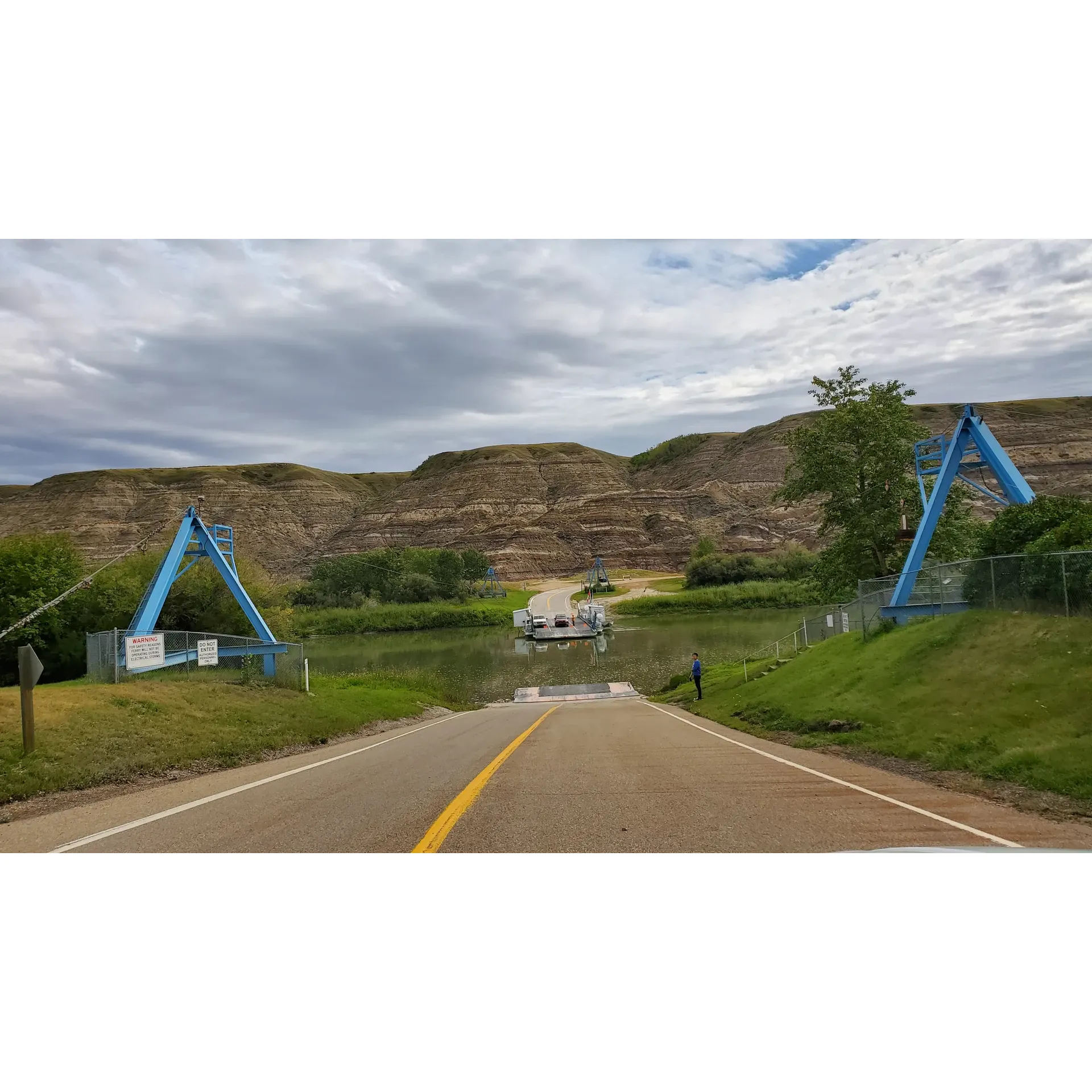 The Bleriot Ferry offers a unique and leisurely journey across the Red Deer River, connecting the picturesque vistas of the North Dinosaur Trail. Terry, the dedicated and charismatic ferry operator, brings life to the experience with his engaging stories and helpful guidance, ensuring a safe crossing for all visitors, even during the tranquil hours of the night. Marvel at the impressive handling of the ferry's pulley system, a testament to the skill and dedication of the operators.

Transporting cars with a pace that allows for peace and reflection, guests are invited to step out and witness the engineering marvel that is the cable ferry system, all while being swept gently over the river's ripples. Passengers frequently commend the unhurried nature of the crossing, recommending this distinctive attraction to those seeking a respite from the hustle and bustle of travel.

Feel the excitement of a bygone era on this historic cable ferry adventure, fully embraced by both locals and travelers as one of Alberta's hidden treasures. Absorb the stunning riverscape, often illuminated by a radiant sunset, creating an unforgettable tableau. The Bleriot Ferry operates with complimentary service, adding another layer of charm to this quaint journey that's worth the detour.

Embrace this piece of living history still in operation since its commissioning in 1913. While the ferry serves as a vital link between Kneehill and Starland Counties, its character enriches the regional narrative—a delightful bonus for those exploring the area's historic and scenic offerings. With camping facilities nearby, it's the perfect stop for adventurers looking to immerse themselves in Alberta's natural beauty and cultural heritage. Description by ChatGPT.