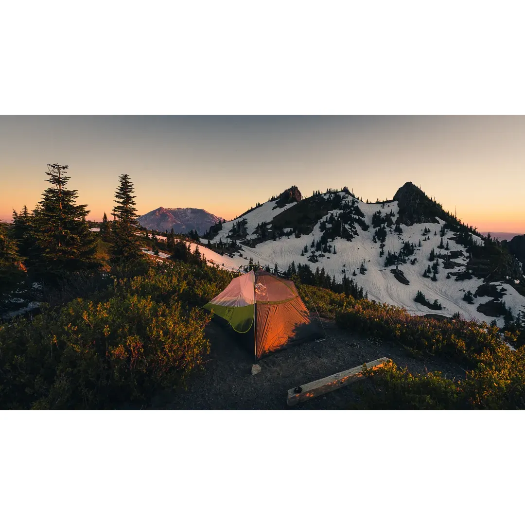 Dome Camp offers an enchanting outdoor experience for those seeking adventure within the breathtaking landscapes surrounding Mt. Saint Helens. This coveted campsite serves as a prime spot for hikers to immerse themselves in the natural beauty of the Pacific Northwest. With just two exclusive campsites available, Dome Camp provides an intimate setting for adventurers who have journeyed along the Boundary Trail #1 to soak in the awe-inspiring surroundings.

Perched strategically between Coldwater Peak and Mount Margaret, the camp beckons with its expansive vistas that sweep across the horizon. Guests have two options for their stay: a lower site nestled in the saddle or a higher vantage point where the panoramic views showcase Mount St. Helens, The Dome, and Mount Whittier in all their glory. The higher site, favored by many, features an exquisite canvas for nature's spectacular display, particularly at dusk when shifting shadows and glowing mountains create a serene ambiance.

The meticulously flat terrain crafted from a soft sand-gravel mix offers an impeccable foundation for setting up tents without the hassle of removing debris, accommodating two two-person tents comfortably. Conditions remain stable and pleasant, with gentle winds that seldom exceed a mild breeze, ensuring a restful night's sleep under the stars.

With no campfires allowed, visitors can fully engage with the environment's purity, enjoying the shifting mists and cloud formations that dramatically alter the landscape at a moment's notice, rendering each glance a new spectacle. The dairy of fog and cloud activity provides an almost theatrical display of natural wonder, especially enchanting as it envelops The Dome and flows into Spirit Lake and the valleys below.

The morning promises encounters with majestic mountain goats along the ridges, adding a playful element to the tranquil setting. The backdrop of woodpeckers' rhythms and distant coyote calls enriches the wilderness atmosphere, drawing visitors closer to the heartbeat of the area.

Guests are reminded to come prepared, as access to water is limited later in the season. Carrying an adequate supply ensures a comfortable and self-sufficient stay. Dome Camp promises a retreat that is both transformative and restorative, offering an unparalleled outdoor experience for those fortunate enough to secure a permit for this magnificent outpost in the shadow of the mountain. Description by ChatGPT.