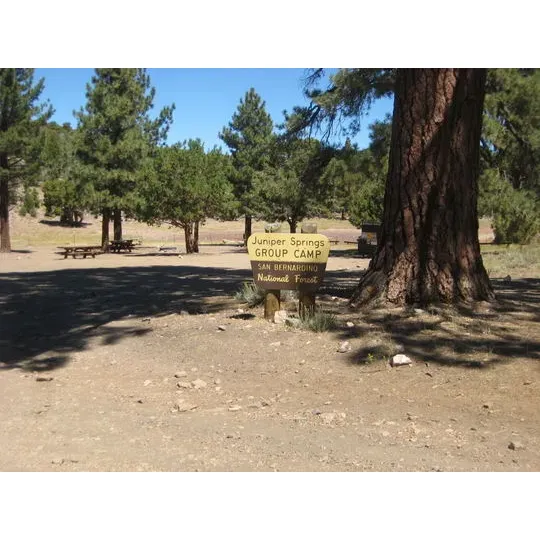 Situated within the beautiful expanse of the San Bernardino National Forest, Juniper Springs Group Campground is an exclusive retreat offering an immersive outdoor experience for adventure enthusiasts. An ideal spot for group gatherings, it can accommodate up to 40 people and eight vehicles, making sure there's ample space for friends and family to connect with nature and each other.

The campground provides the perfect backdrop for a rugged, off-the-grid getaway. With challenging terrain leading up to the site, a high clearance 4x4 vehicle is required to navigate the ruts and rocks—a true testament to the wilderness that awaits. The access road, 2N01, presents a thrilling drive for experienced off-roaders looking for that extra bit of excitement before settling into the camp.

This expansive private campground sets the stage for a memorable group stay. Equipped with essential amenities such as picnic tables, a fire pit, and a non-potable water source, the site ensures basic comforts while encouraging a rustic camping vibe. The outdoor bathroom facilities highlight a close-to-nature feel, reminding guests of the simplicity of wilderness living.

Surrounding the campsite, visitors will discover a picturesque field that transforms into a serene pond following a storm, adding to the picturesque setting. A quaint meadow and a small mountain adjacent to the campground provide scenic vistas and several hiking opportunities, inviting guests to explore the lush surroundings. For the more adventurous, the location is within reach of fantastic off-roading routes.

The area is not only rich with natural beauty but also conducive to social gatherings, as the available space and shaded areas ensure comfort for large groups. Campers are encouraged to practice Leave No Trace principles, carrying out any trash to preserve the pristine condition of the environment.

Juniper Springs Group Camp offers a unique blend of excitement for outdoor adventurers and tranquility for those seeking a peaceful retreat. Whether you’re looking to bond over a campfire, hike through unspoiled trails, or explore rough terrains with your vehicle, this campground provides a compelling escape from the hustle and bustle of city life—all set in a truly majestic, green valley. Description by ChatGPT.