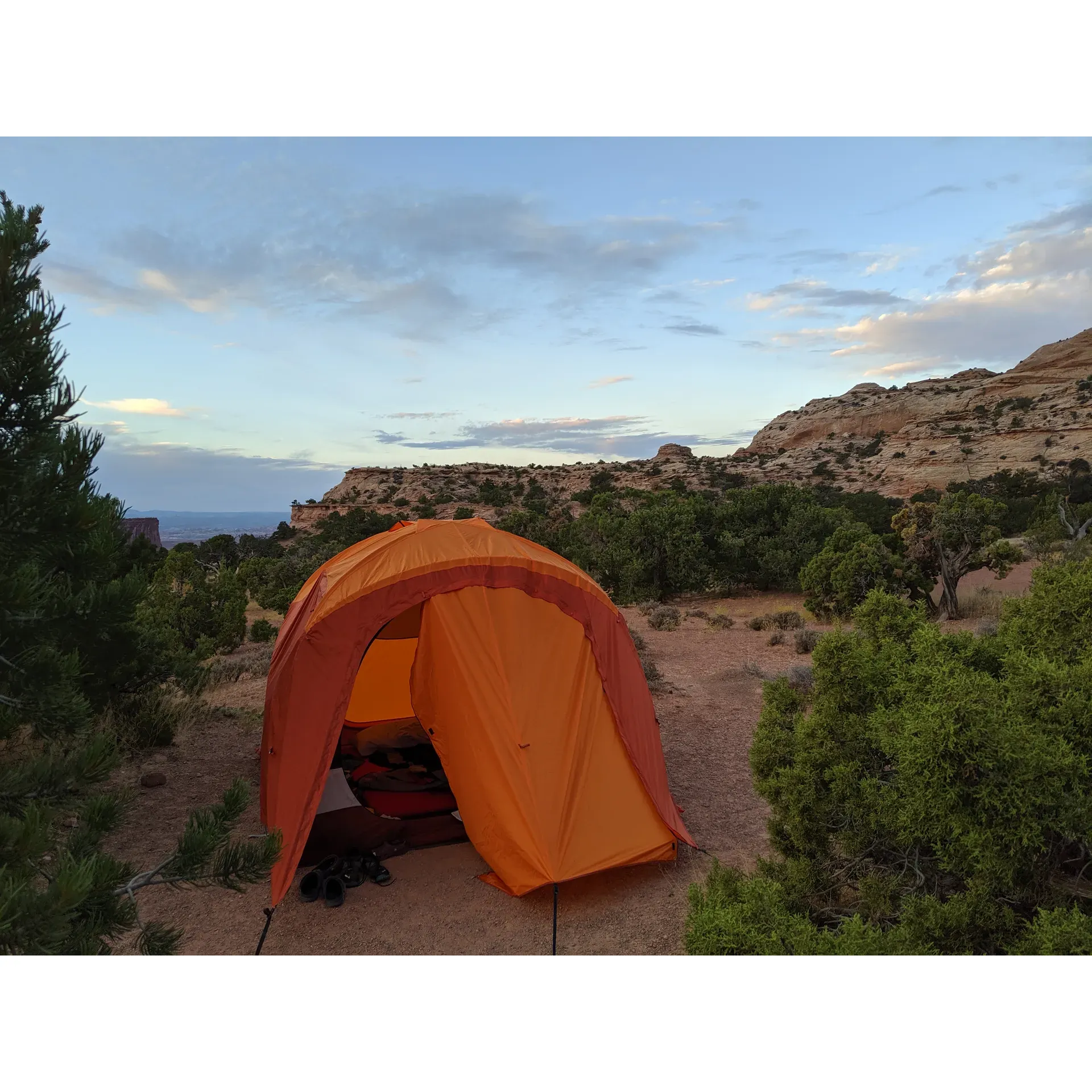 Experience the tranquility and natural beauty of Island in the Sky (Willow Flat) Campground, where the majestic landscape of Canyonlands National Park envelops you in its stunning vistas. With a reasonable rate of $20 per night, this prized campground offers well-maintained sites that come with the convenience of on-site bathrooms and garbage facilities, ensuring a comfortable stay amidst the wilderness.

Perfect for early risers and nature enthusiasts, the campground provides an ideal starting point for a breathtaking sunrise walk, rewarding visitors with unparalleled views that make every moment memorable. The scenic lookout is easily accessible, offering a serene spot to witness the awe-inspiring skies as they greet the day.

Each camping spot includes a covered table area that provides a private setting for you to relax and enjoy your meals while being surrounded by panoramic landscapes. The campground's thoughtful layout encourages seclusion and tranquility, allowing you to immerse yourself in the peaceful surroundings and star-filled nights, making it a stargazer's paradise.

While there is no water available, guests are encouraged to bring their own supplies to maintain hydration and comfort during their stay. The remote nature of the campground, about 45 minutes from the Island in the Sky entrance, adds to the allure of an off-the-beaten-path adventure. With vault toilets kept in decent condition, your basic needs are met allowing you to focus on the grandeur of the area.

The camping spots at Island in the Sky (Willow Flat) Campground are sought-after, operating on a first-come, first-served basis, with a convenient no-contact payment system for sites, emphasizing ease and simplicity. The spacious, secluded spots provide ample room to unwind and connect with nature. Visitors are encouraged to mark their chosen site, ensuring a stress-free experience as they explore the enchanting surroundings.

Strategically positioned as a central hub for all neighboring parks and sights, this beautiful campground serves as the perfect base for adventurers looking to explore the grandeur of Canyonlands National Park and beyond. Remember to arrive early to secure your slice of paradise at this incredible camping destination, where the natural splendor of the desert landscape awaits. Description by ChatGPT.