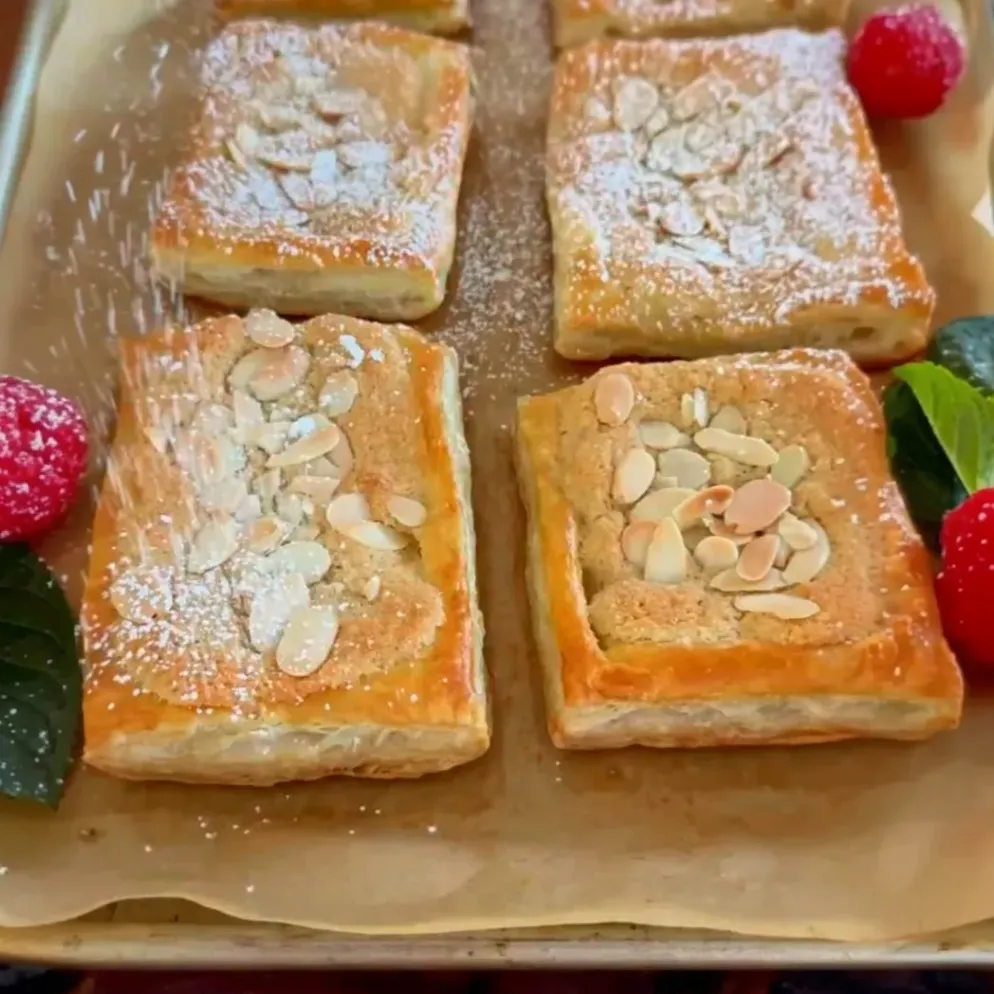 These delightful tarts combine flaky puff pastry with a rich, aromatic almond filling, topped with sliced almonds and powdered sugar, making them an exquisite dessert or sweet snack.