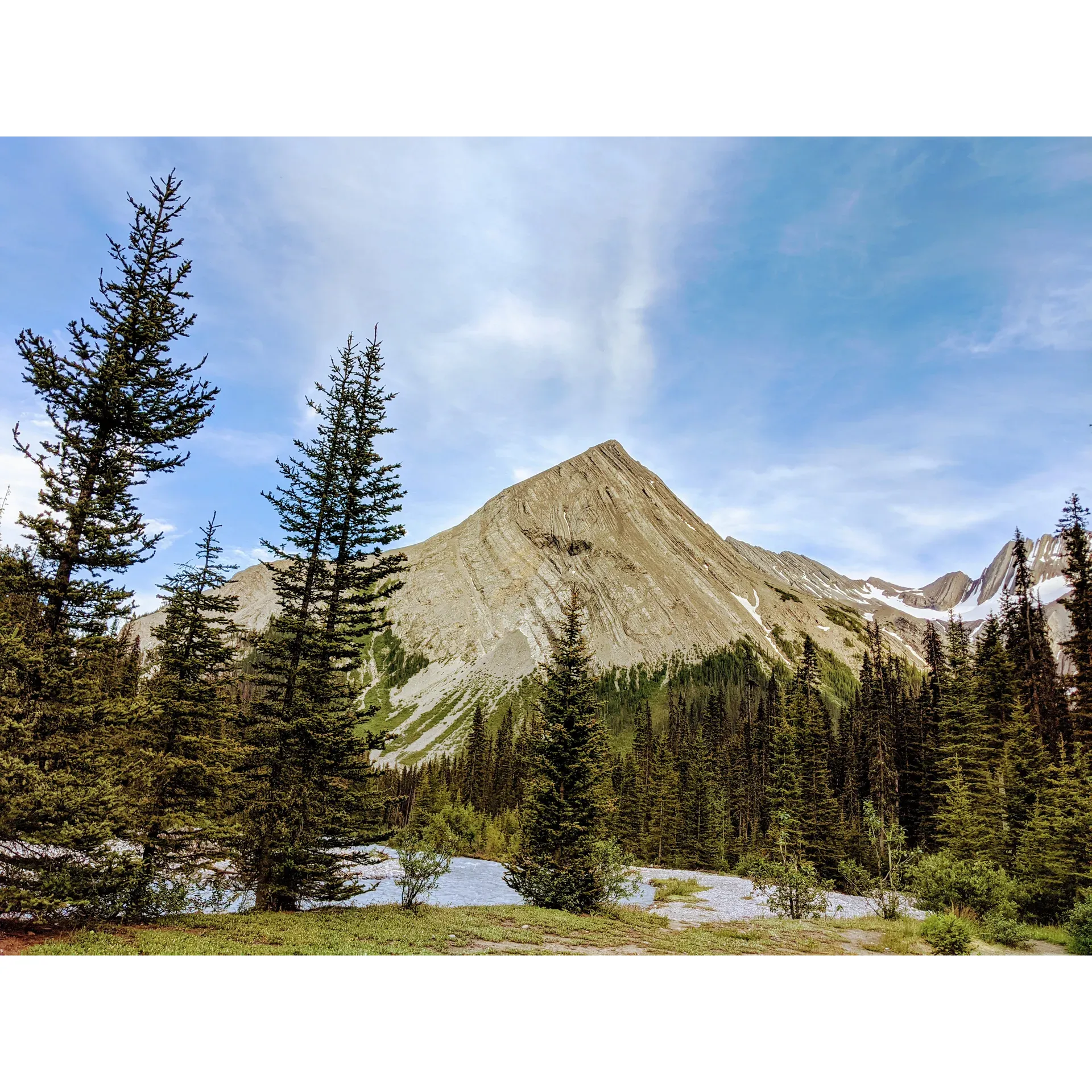 Forks Backcountry Campground offers a serene escape in the heart of Kananaskis Country, acclaimed by many as a premier destination for outdoor enthusiasm and scenic relaxation. The campground is surrounded by the raw beauty of the Canadian wilderness and stands out for its accessibility, comfort, and ample amenities that cater to both seasoned backpackers and those new to backcountry adventures.

A true outdoorsman's haven, the campground boasts a plethora of firewood, with a stroll along the Upper Kananaskis River rewarding campers with fuel for their fires and an axe on-site for added convenience. The well-thought-out communal area serves as a social hub, featuring a fire pit, ample seating, and secure bear lockers, ensuring safety for both wildlife and guests. This gem of a spot is perfect for a peaceful retreat or as a base for further exploration.

Accommodating a maximum of 15 sites at a modest rate, the campground ensures a sense of seclusion without feeling isolated, as the sites are generously spaced out and shrouded by trees, giving each plot a touch of privacy. Moreover, the proximity to the river enriches the experience as the gentle sounds of flowing water lull visitors to sleep, while the water itself provides a source of refreshment, easily treated with a quality micro water filter.

Cleanliness is a noted feature, with the outhouses being well-maintained, adding to the comfort of campers. For those seeking adventure, the campground is strategically located at the confluence of trails heading to Three Isle and Turbine Canyon, making it an ideal stopover or base for embarking on hikes to the surrounding majestic landscapes.

The campground's ease of access, combined with its beautiful setting along the Upper Kananaskis River, makes it a highly recommended choice for families, beginners, and experienced nature lovers alike. Its capacity to serve as a springboard to nearby lakes and peaks only enhances its appeal.

Reservations are a breeze with online booking via the AlbertaParks website, allowing for planning up to three months in advance. With its harmonious blend of convenience, natural splendor, and a welcoming atmosphere, Forks Backcountry Campground remains a cherished spot among those seeking solace and adventure in the splendor of Kananaskis Country. Description by ChatGPT.