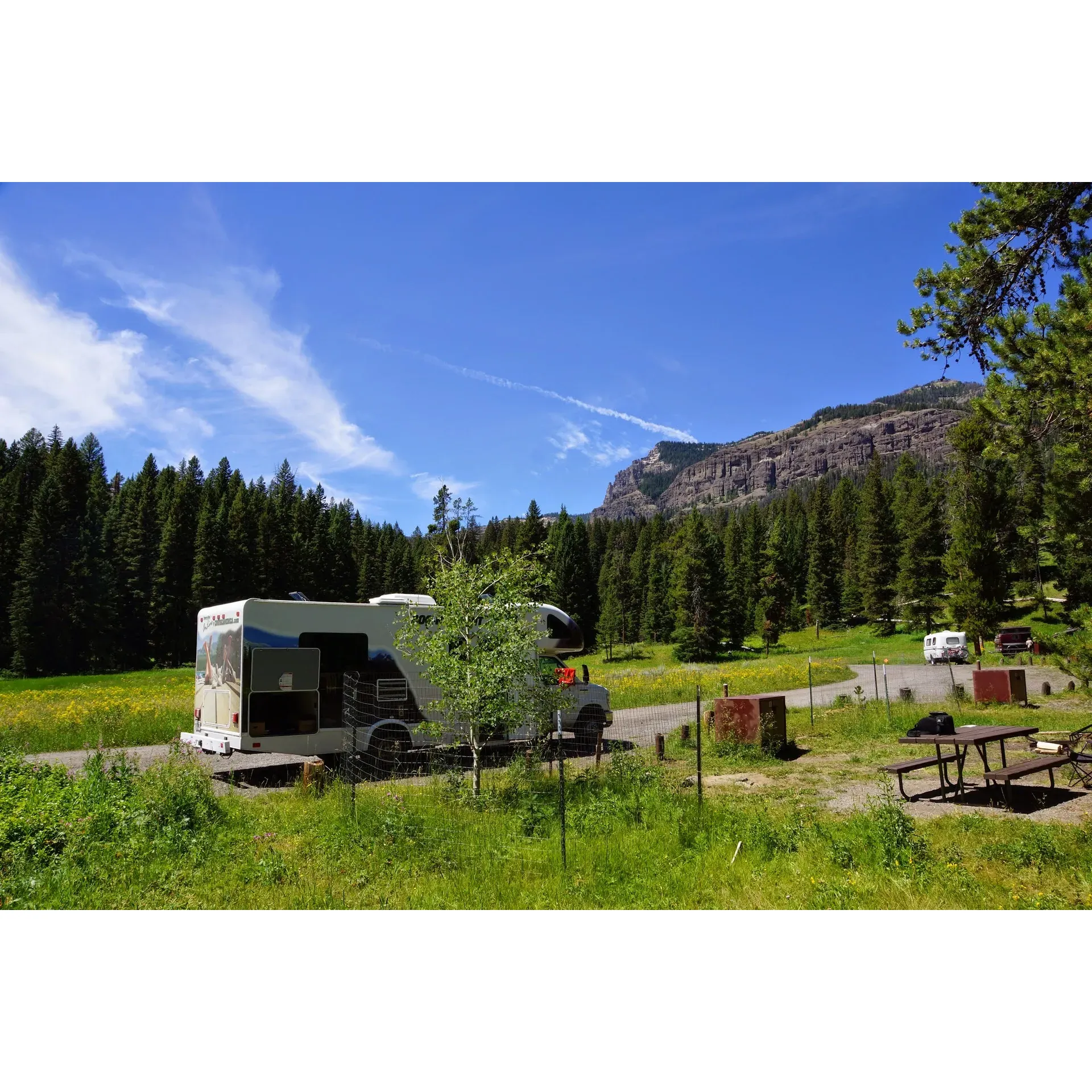 Pebble Creek Campground emerges as a cherished retreat for nature enthusiasts and outdoor adventure seekers alike. Visitors are treated to a serene and unspoiled setting where the harmonious symphony of native wildlife, from birds to bison, provides an immersive backdrop to the camping experience. The crisp, clear sounds of a small river create a tranquil atmosphere as it flows adjacent to the camp sites, letting you experience nature's rhythm up close.

This campground boasts prime positioning for guests looking to explore the majestic Lamar Valley or venture to the picturesque towns of Silver Gate and Cooke City. Its strategic location serves as a splendid base for day trips throughout Yellowstone's vast landscapes, including the formidable Mammoth Hot Springs.

Camping at Pebble Creek is an opportunity to reconnect with the raw essence of the wild. The simplicity of waterless toilet facilities and the absence of electrical distractions only enhance the feeling of being at one with the surrounding environment. A true gem for those who appreciate top-notch campsites, Pebble Creek offers the essentials such as tent pads, picnic tables, and bear boxes, combining comfort with natural living.

For the adventurous families, the Pebble Creek Trail provides easy access and a family-friendly hiking experience that even the youngest explorers can enjoy. The icy but inviting waters of the creek are ideal for a rejuvenating foot soak after a day of hiking.

A sense of community and quietude is preserved by the prohibition of generators, ensuring that the only sounds you hear are the whispering wind through the trees and the playful babble of the creek. This commitment to tranquility complements the excellent wildlife viewing opportunities visible even from the seclusion of your campsite.

The campground's hosts epitomize the spirit of Yellowstone with their warm hospitality and dedication, ensuring that the camp facilities, including the well-maintained pit toilets and water spigots, meet the needs of all guests. With over two decades of service, the hosts are a fount of knowledge and an integral part of the campground's charm.

Although slightly more remote compared to other sites within the park, the unique location only adds to the allure, with scenic drives through bison herds enhancing the journey to and from Yellowstone's renowned attractions. Pebble Creek Campground is not just a place to stay; it's a destination that beckons visitors back, promising a timeless, quiet escape in the heart of nature's splendor. Description by ChatGPT.