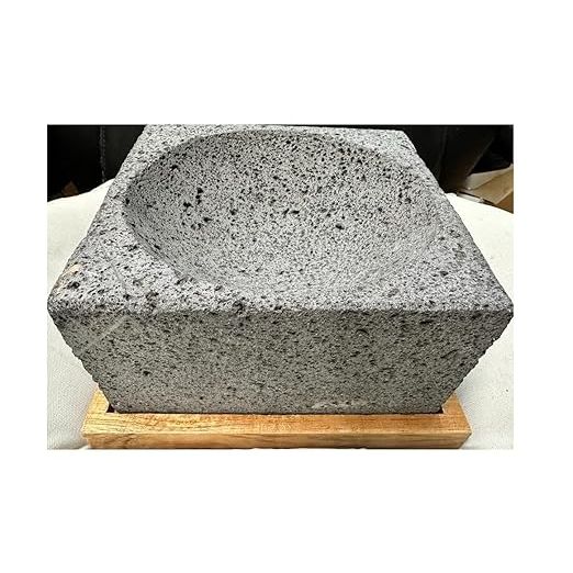 The Made in Mexico Guacamole Maker is a large 9" square tool used for preparing authentic guacamole and salsa. The product is made from genuine volcanic lava rock, giving it a traditional and rustic Mexican style. It comes with a wooden base for stability and ease of use.