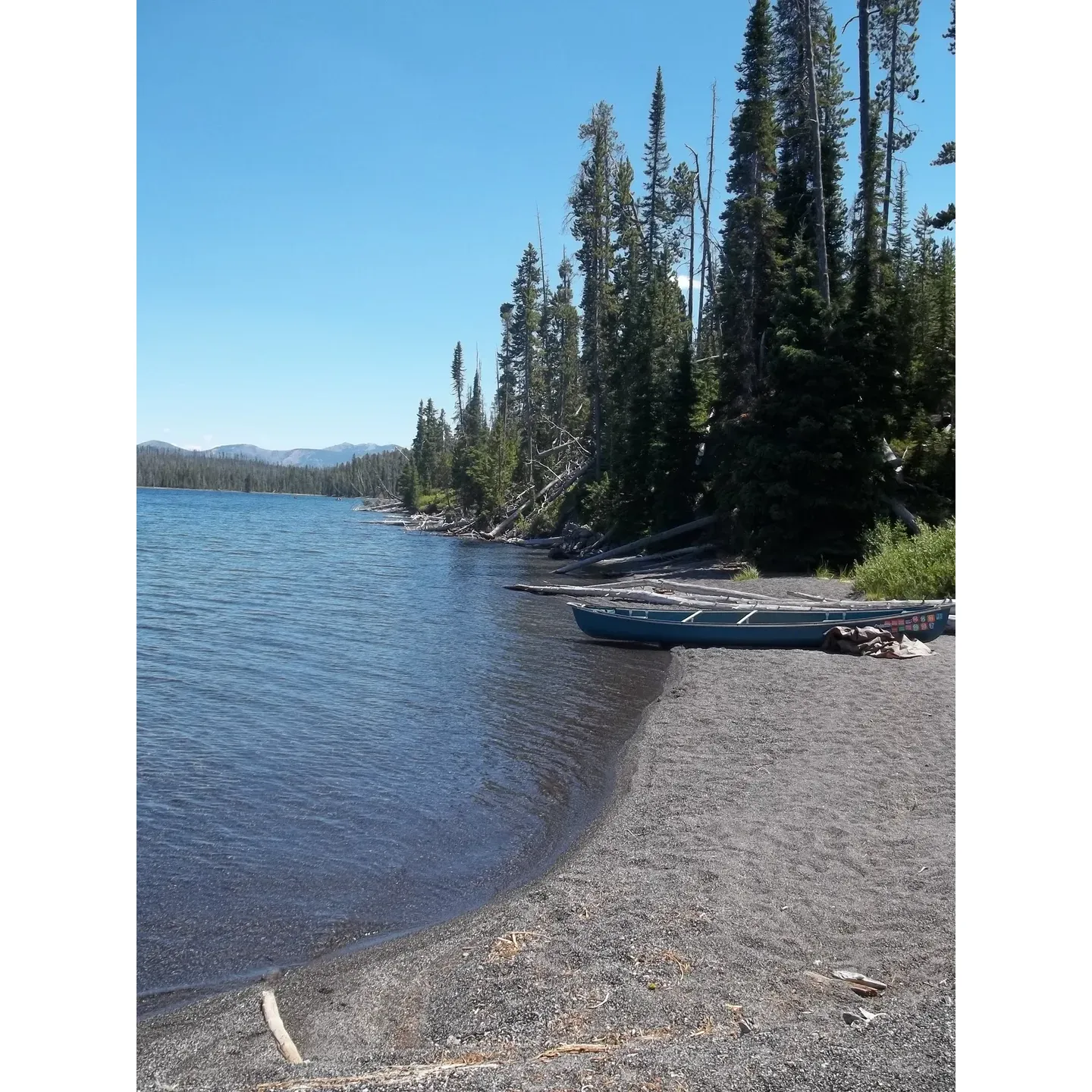 Channel offers outdoor enthusiasts a serene and convenient retreat along the majestic shores of Lewis Lake. This charming site presents an unbeatable accessibility, perfect for adventurers embarking on an early morning journey or seeking a restful endpoint to their day. With a gentle approach to both the tent area and the inviting beachside cook spot, guests can ease into their camping experience without the challenge of steep climbs or difficult terrain.

The pristine and well-structured tent site, elevated just enough from the beach, provides a sheltered backdrop for restful slumber under the stars, while still offering the delightful soundtrack of the gentle lake waters nearby. Visitors can enjoy the simplicity of outdoor cooking with the great cook area placed right at the beach's edge, allowing for meal preparations accompanied by breathtaking views and the soft rustling of the lake breeze.

Despite the historical touch of nature’s transformation left by the fires of '88, Channel boasts the resilience of nature with the survival of a few majestic old-growth trees that stand sentinel at the site, adding character and a sense of timelessness to the landscape.

The region's rejuvenation is tangible, and the presence of a vault toilet ensures a touch of modern convenience is always within reach, albeit just a short climb away. With the tranquil setting, ease of access, and the pure natural beauty that envelopes the area, Channel stands as an idyllic spot for campers seeking a harmonious and picturesque outdoor haven. Description by ChatGPT.