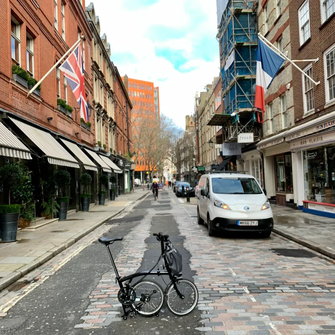 West End conservation area street with a central sundial column, boutiques & restaurants.