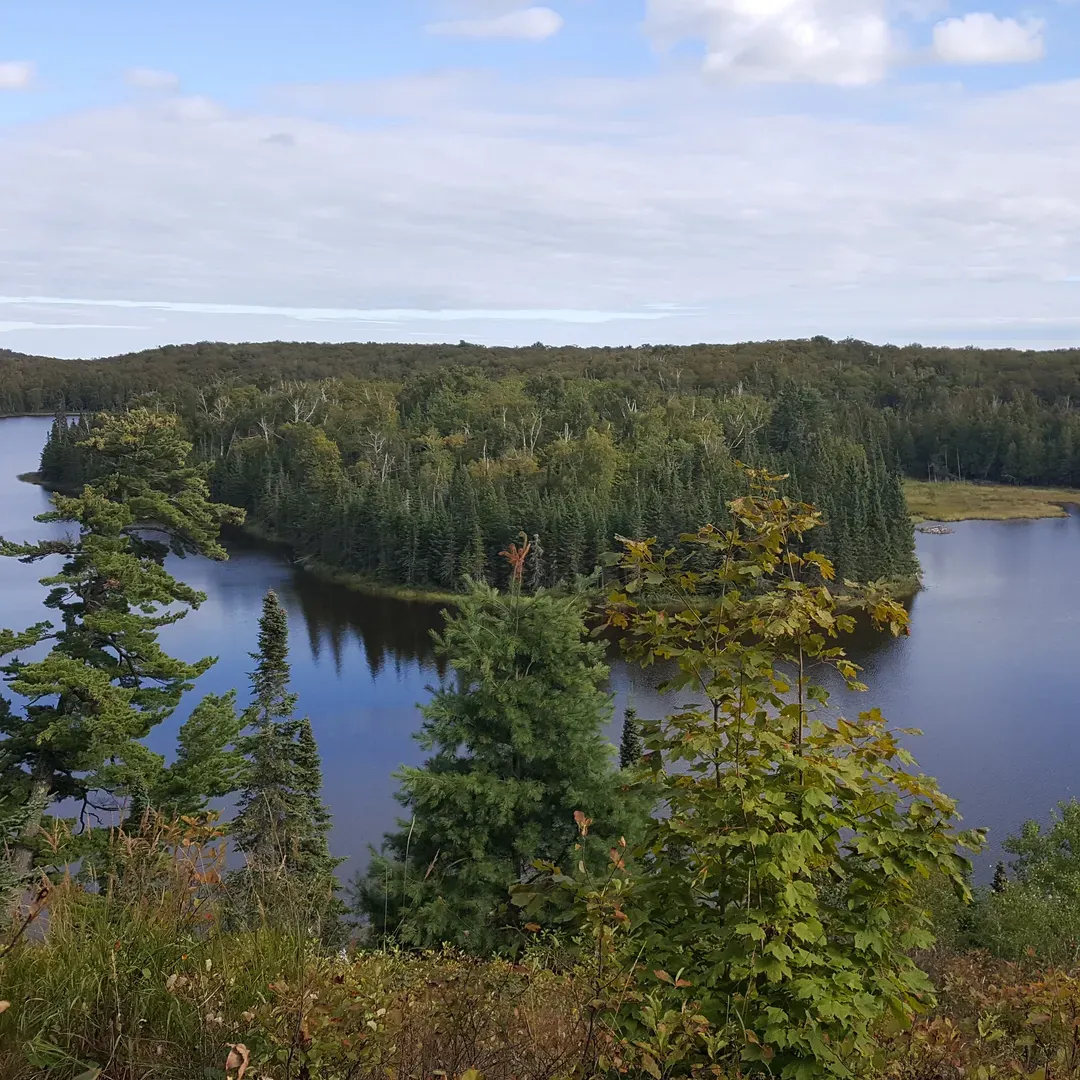 West Lake Agnes Camp offers a serene and undisturbed getaway for outdoor enthusiasts seeking an authentic backcountry experience. Set just a mile off the Lake Superior hiking trail and perched by the picturesque Lake Agnes, this multi-site campground is a true retreat for those looking to immerse themselves in nature.

The approach to the camp involves a challenging trek over rugged terrain, culminating in a satisfying hill climb, making it a rewarding venture for seasoned hikers and adventure-seekers. The sites are designed for a closer encounter with the wilderness, ensuring a primitive camping environment that prioritizes minimal impact on the natural area. 

Visitors can enjoy the tranquility of the camp, complemented by quick access to the serene lake – perfect for quiet contemplation or a refreshing dip. It's an ideal spot for those traversing the Superior Hiking Trail, offering a peaceful interlude for multi-day trekkers.

Admirably maintained, the campsite shines with cleanliness, barely showing signs of human footprint, thanks to the responsible practices of previous campers. A designated latrine is conveniently located just a short walk from the primary camp area, emphasizing the site’s commitment to eco-friendly practices.

Adding to the safety and convenience, bear poles are installed to ensure that wilderness adventurers can secure their provisions with ease, allowing for an undisturbed night's rest under the stars.

Notable for its breathtaking scenery, West Lake Agnes Camp is particularly enchanting in the fall, when the foliage presents a spectacular display of colors, creating a stunning backdrop for camping memories. Although popular and sometimes bustling with fellow nature lovers, the campsite retains an air of calm and quietude that is cherished by those fortunate enough to claim a spot by its shores.

For those in search of an off-the-beaten-path camping sanctuary with the allure of untouched wilderness and sparkling waters, West Lake Agnes Camp is an exemplary destination. Description by ChatGPT.