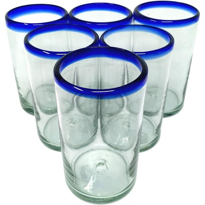 The Dos Sueños Hand Blown Mexican Drinking Glasses are a set of six glasses with cobalt blue rims. Each glass has a capacity of 14 oz, making them suitable for a variety of beverages including water, juice, or cocktails.